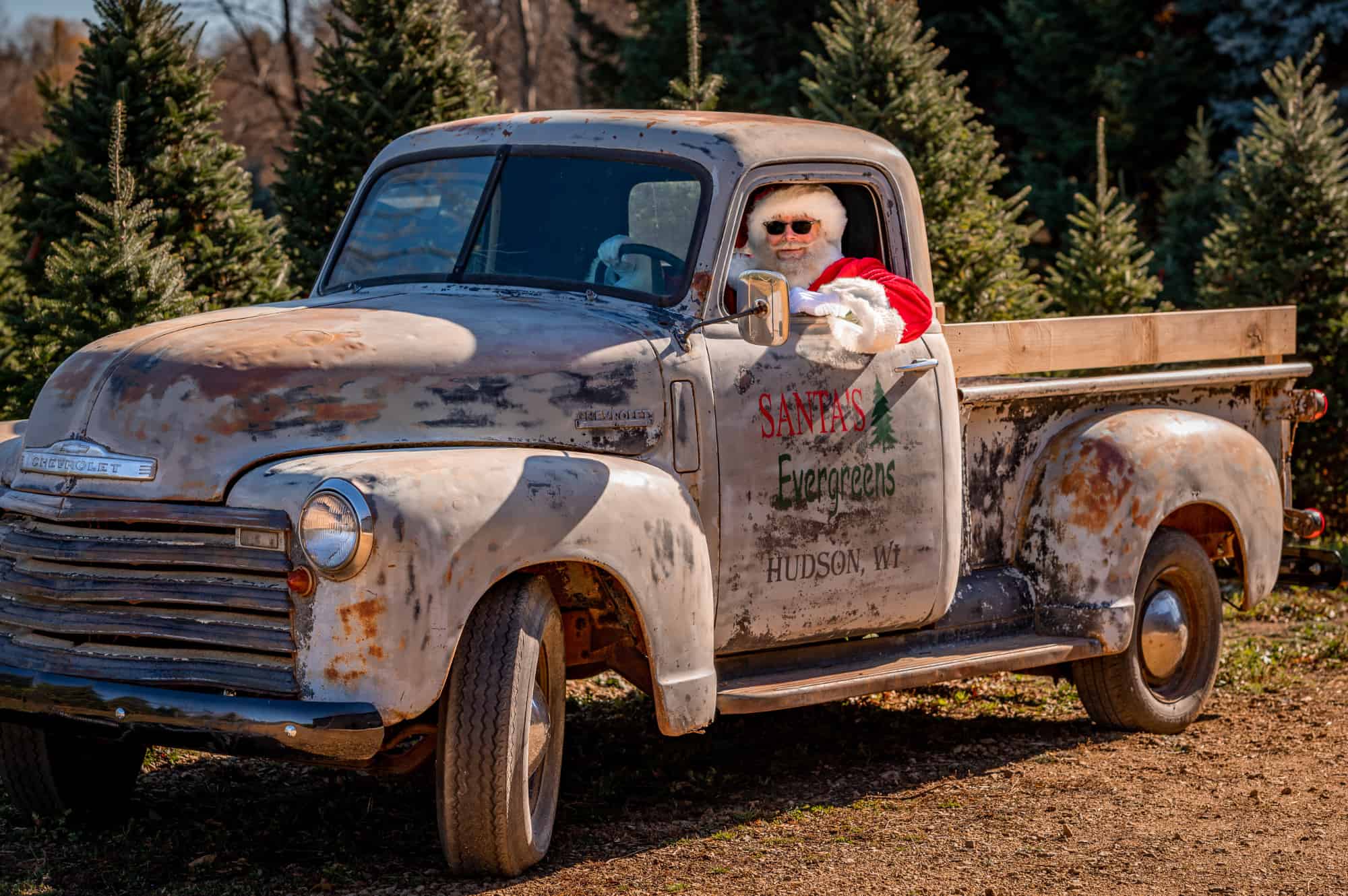 Santa with sunglasses in old truck.