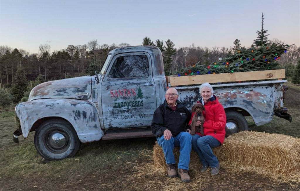 Couple and dog next to old truck.